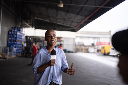 Reporter talking on the microphone in a warehouse