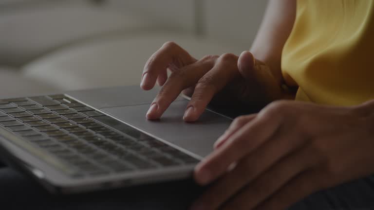 Close up of African Amerian woman hands using laptop touchpad - pinch, swipe and scroll