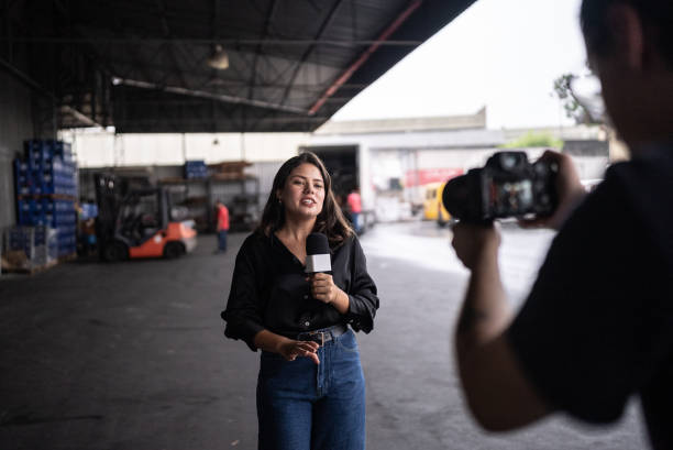 Reporter talking on the microphone in a warehouse