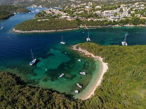 Aerial view of beautiful beach and amazing coast in Ionian sea. Sailboat and catamarans anchored in bay near Syvota, Greece
