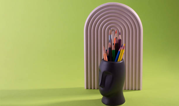 istock Multi Colored Pencils are placed in Vase Face Form Against a Green. 1466096993