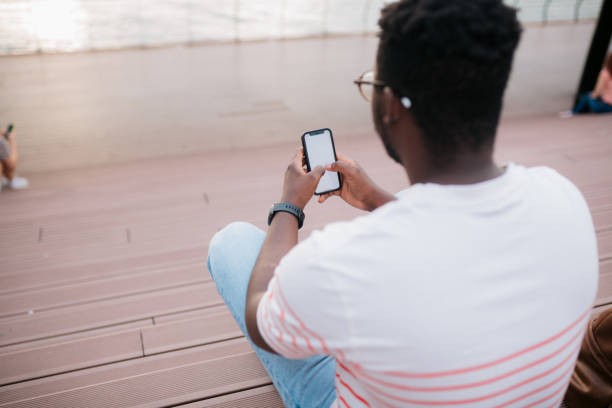 istock Young man sitting on the steps outside in the city using mobile phone 1466100461