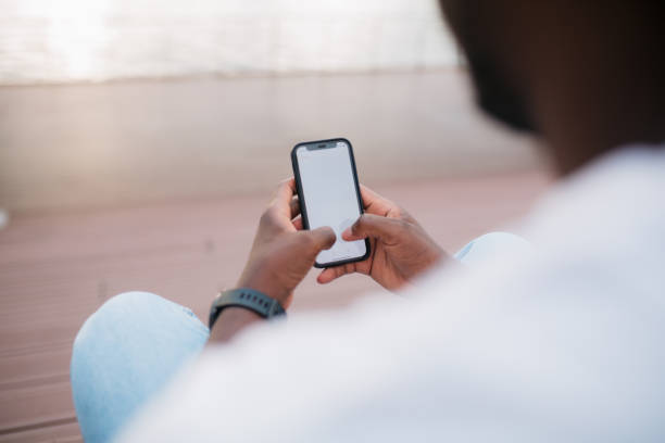 istock Close-up of a man using mobile phone sitting outside 1466100514