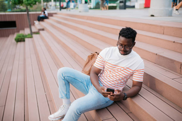 istock Young man using mobile phone sitting on the steps outdoors in the city 1466100530