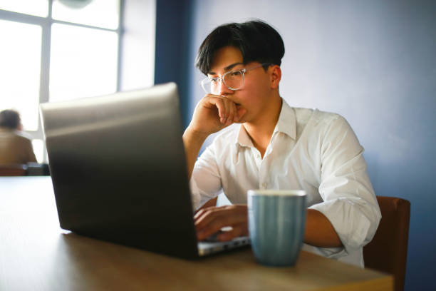 istock Young man with slanting eyes working hybrid remotely from laptop in cafe. 1466102822