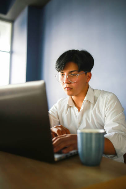 istock Young man with slanting eyes working hybrid remotely from laptop in cafe. 1466102892