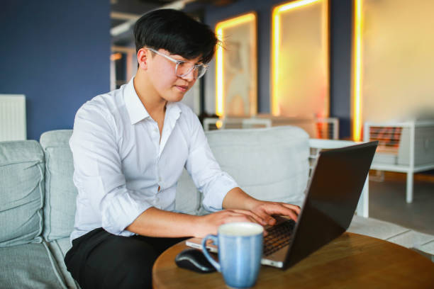 istock Young man with slanting eyes working hybrid remotely from laptop in cafe. 1466102968