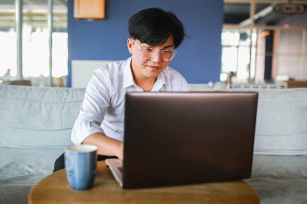 istock Young man with slanting eyes working hybrid remotely from laptop in cafe. 1466102975