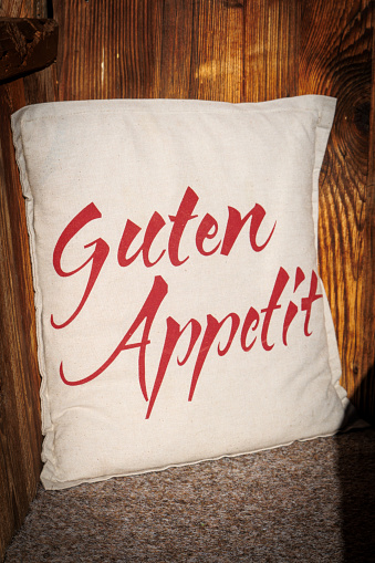 on a white cushion on a bench are the german words Guten Appetit