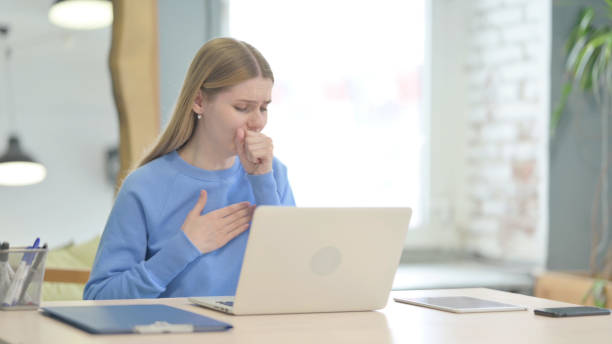 istock Coughing Sick Young Woman Working on Laptop 1466112175