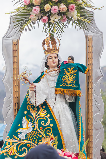 Procession of San Cristobal and the Virgin of Carmen with green dress and golden accessories and other colors on her altar, surrounded by devotees, located in Shupluy, Ancash, Peru
