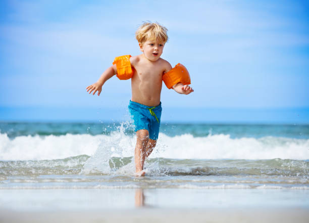 istock Boy in inflatable shoulder straps run from the ocean waves 1466125858