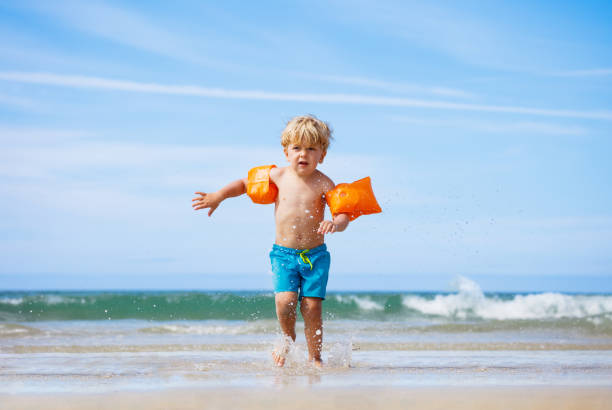 istock Boy in inflatable shoulder straps run from the sea waves 1466125901