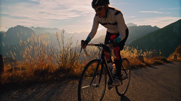 Determined cyclist cycling on road in sunny sunrise mountains