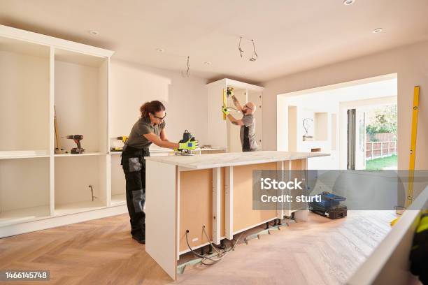 Kitchen Fitters Installing Some Cabinets Stock Photo - Download Image Now - Renovation, Kitchen, Home Addition