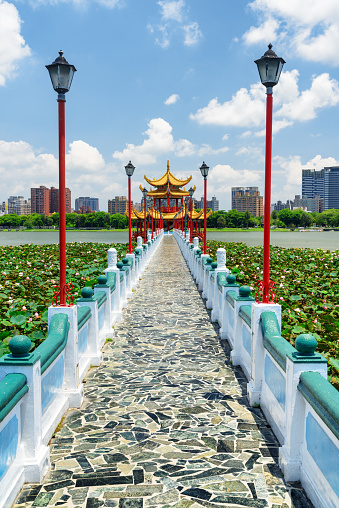 Awesome view of bridge leading to Wuliting at Lotus Lake in Kaohsiung, Taiwan. The traditional Chinese red pavilion with golden roof is a popular tourist attraction of Asia.