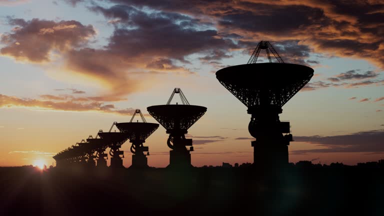 Astronomical sattellite dishes in a row pinting up under the sunset sky