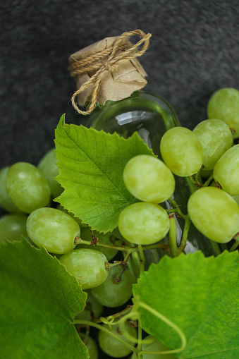 grape oil. organic oils. Green grapes with leaves and oil in a transparent bottle on a slate background.