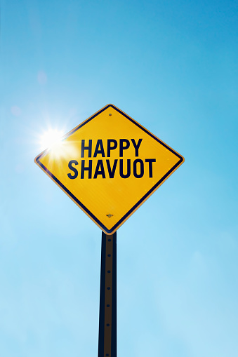 Happy Shavuot  sign in front of a blue sky