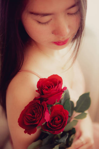 woman in pajamas colored rose gold With a red rose on the bed resting in the morning, Background concept, closeup flower.
