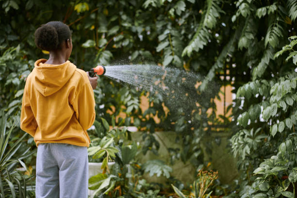 Woman Watering Trees in Backyard