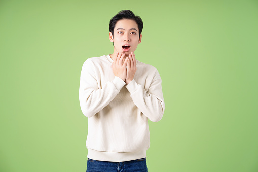 Portrait of young Asian man posing on green background