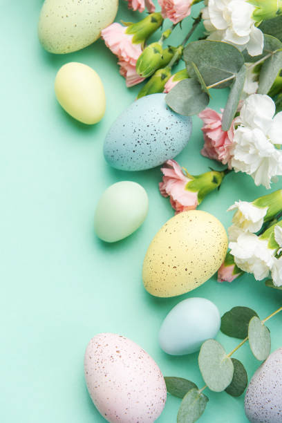 istock Easter colored eggs and a bouquet of white and pink carnations with eucalyptus branches on a soft green background. 1466222175