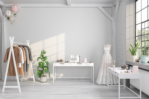 Tailor Studio Interior With Sewing Machine, Clothes On Coat Hanger And Wedding Dress On Mannequin