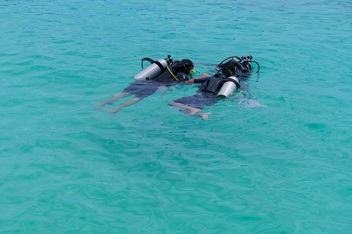 Dive master training a couple for first dive in a tropical turquoise island beach