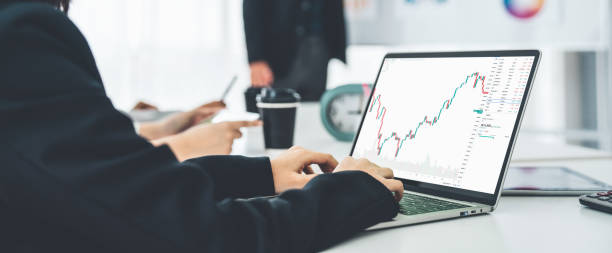 istock Businesswoman in analyze stock market data using laptop computer proficiently at the office while attending a group meeting with business team . 1466229610