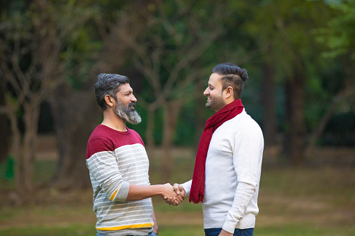 Two indian man shaking hand each other at park.