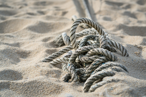 An old rope used to tie a boat Lay on the beach at thailand