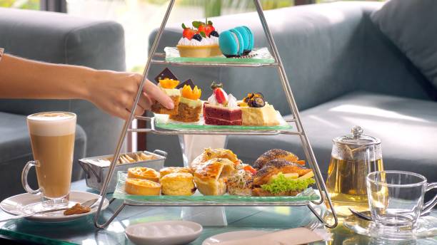 woman hand take slice of cake from a towering display of afternoon tea - afternoon tea fotos imagens e fotografias de stock