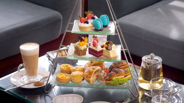 istock Colorful afternoon tea table with glass teapot, fresh fruit cakes 1466246375