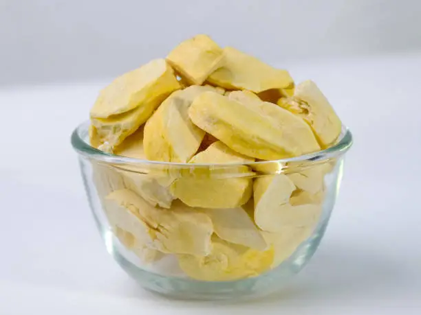 Photo of Freeze-dried durian, is a processed fruit that retains the nutritional value of food. Freeze-dried durian in glass bowl isolated on white background.