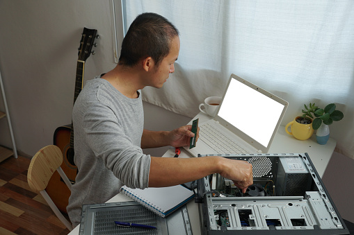 asian men repairing a computer with learning online at home.