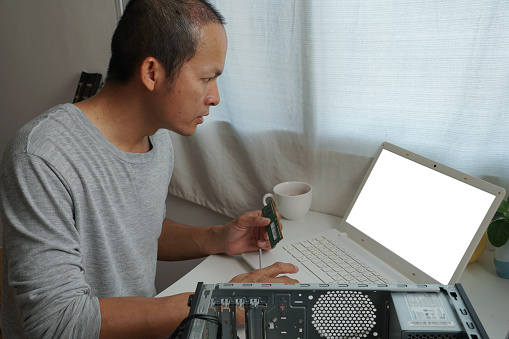 asian men repairing a computer with learning online at home.