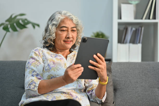 istock Happy middle aged woman browsing wireless Internet on tablet, relax on sofa at home. Elderly technology concept. 1466262023