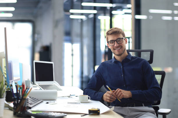 istock Handsome male architect looking at camera and smiling while sitting in the office. 1466263456