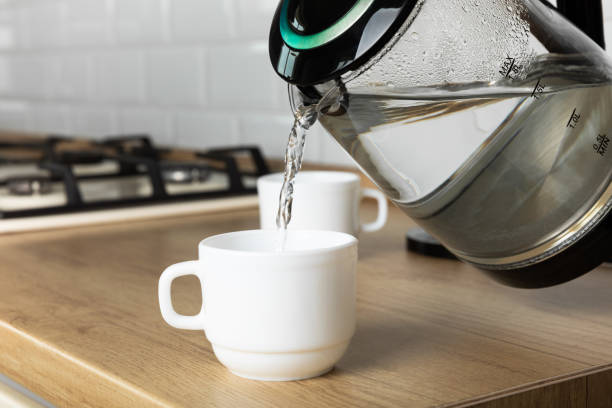 istock A man makes tea using boiling water from an electric kettle in the kitchen at home. It's time to have breakfast and drink tea. Modern electric kettle on a wooden table. Kettle for boiling water. 1466265615