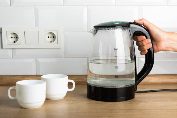 istock A man makes tea using boiling water from an electric kettle in the kitchen at home. It's time to have breakfast and drink tea. Modern electric kettle on a wooden table. Kettle for boiling water. 1466265639