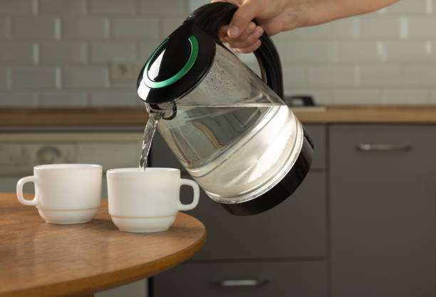 istock A man makes tea using boiling water from an electric kettle in the kitchen at home. It's time to have breakfast and drink tea. Modern electric kettle on a wooden table. Kettle for boiling water. 1466265782
