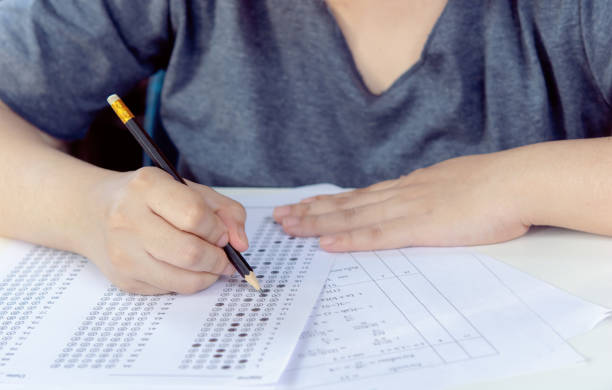 istock Students hand holding pencil writing selected choice on answer sheets and Mathematics question sheets. students testing doing examination. school exam 1466270424