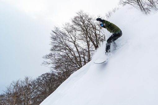 A freestyle snowboarder riding in Shizukuishi, Iwate. Famous powder of North Japan.