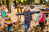 Playful kids running with their arms outstretched in autumn day.