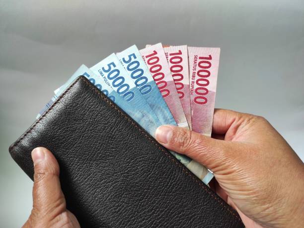 istock Human hands holding 50000 and 100000 rupiah banknote 1466277096