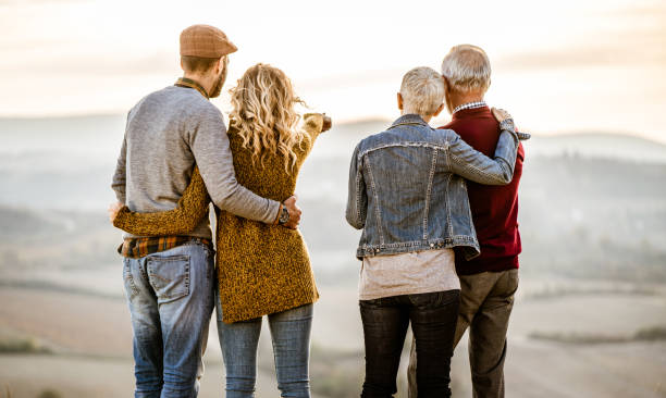 istock Back view of two couples standing embraced on a hill and looking at view. 1466277275