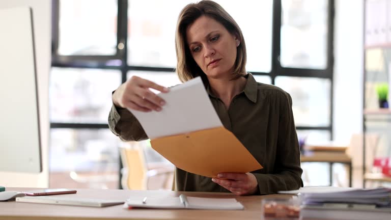 Mail correspondence of a businesswoman opening paper letter reading information about watching news