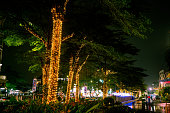 Wide view of decorated medium tree with yellow Tumblr lamp in front of mall during the night