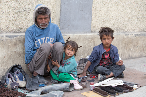 LEH, INDIA - SEPTEMBER 08 2014: An unidentified beggar family begs for money from a passerby in Leh. Poverty is a major issue in India